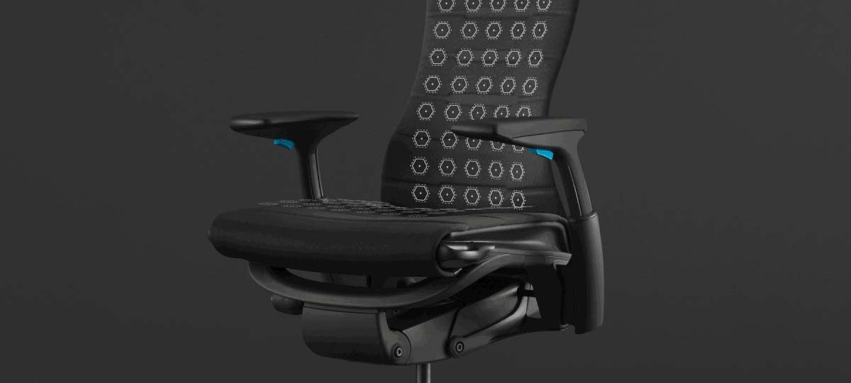 Vooraanzicht van een zwart-blauwe Embody-gamingstoel van Herman Miller, bedekt met witte afbeeldingen die de zitting en rugleuning accentueren.