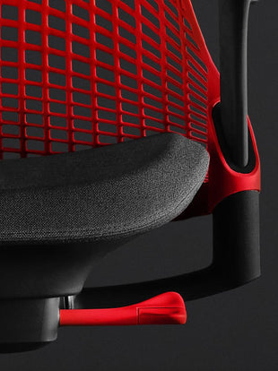 Close-up vooraanzicht van een rode en zwarte Sayl-gamingstoel van Herman Miller, met het voorgevormde zitkussen en de rode rugleuning.