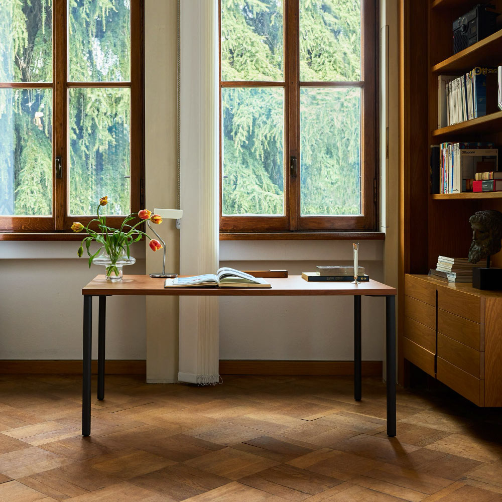 Een Herman Miller OE1 bureau met een walnoot blad en marineblauwe poten. Met een crème HAY Apex lamp.
