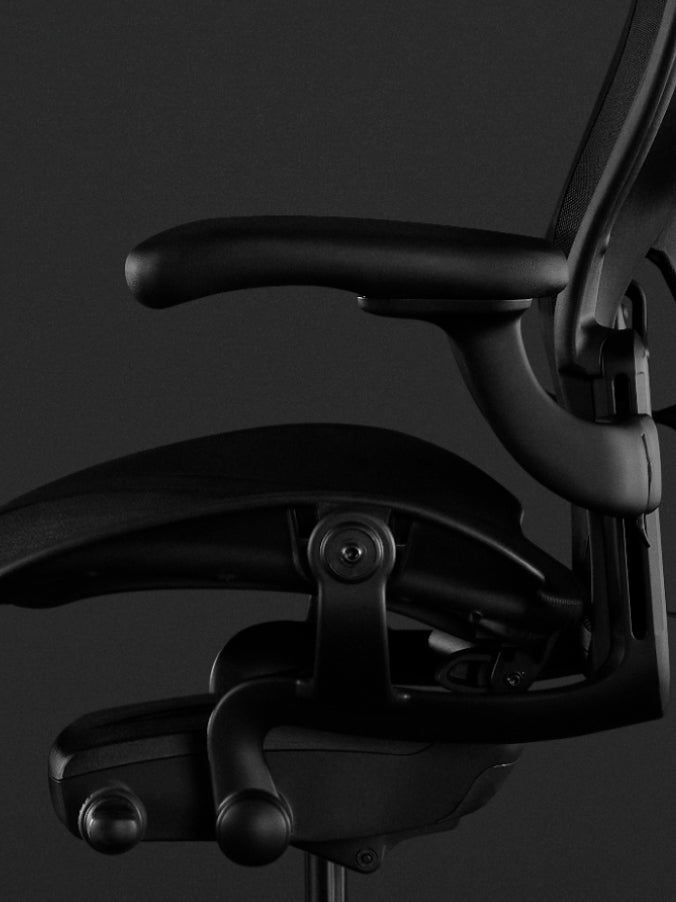 Zijaanzicht van een zwarte Aeron-gamingstoel van Herman Miller, met volledig verstelbare armleuningen.