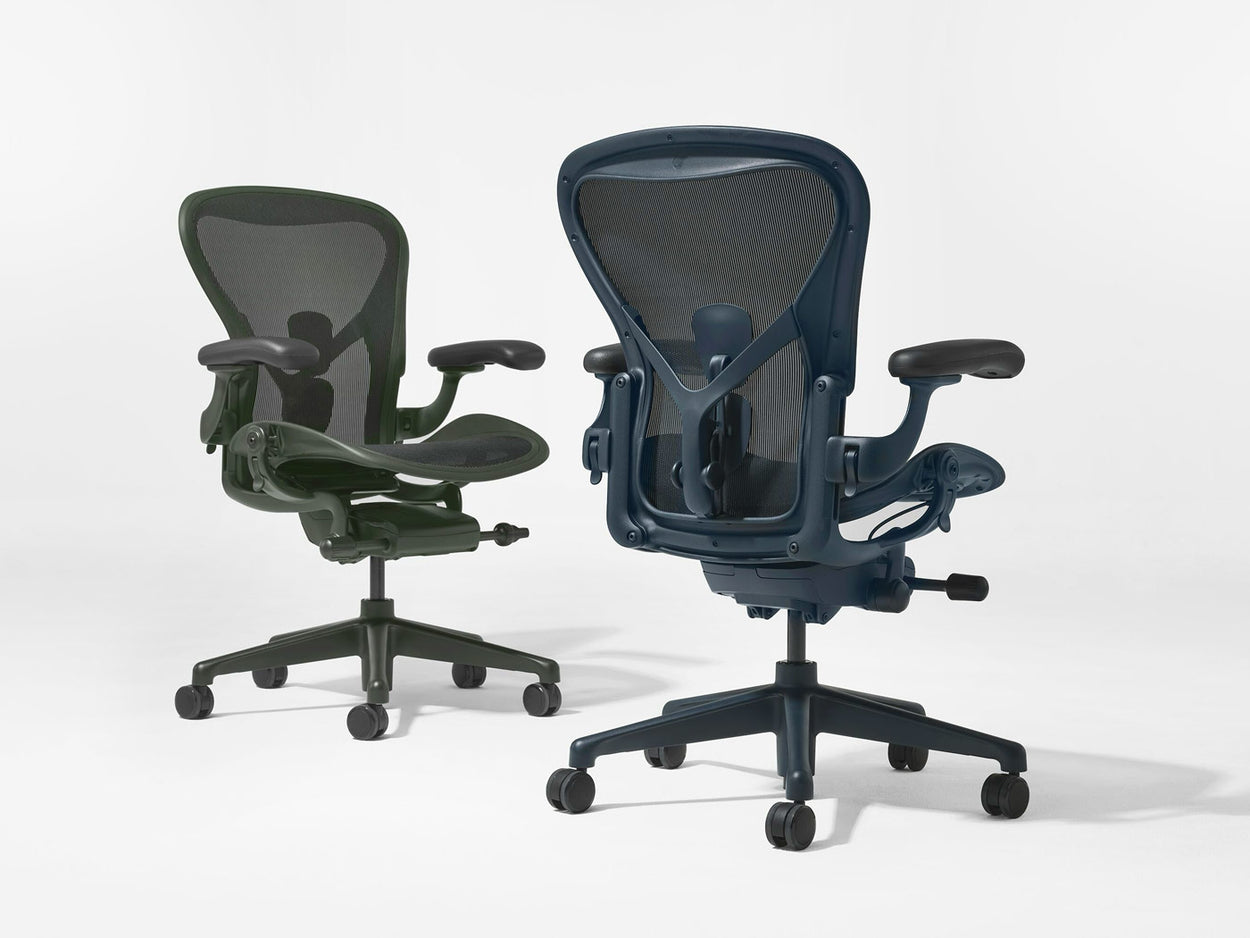 Twee Herman Miller Aeron-bureaustoelen in Jasper groen en Nightfall blauw, gefotografeerd in een witte studio.