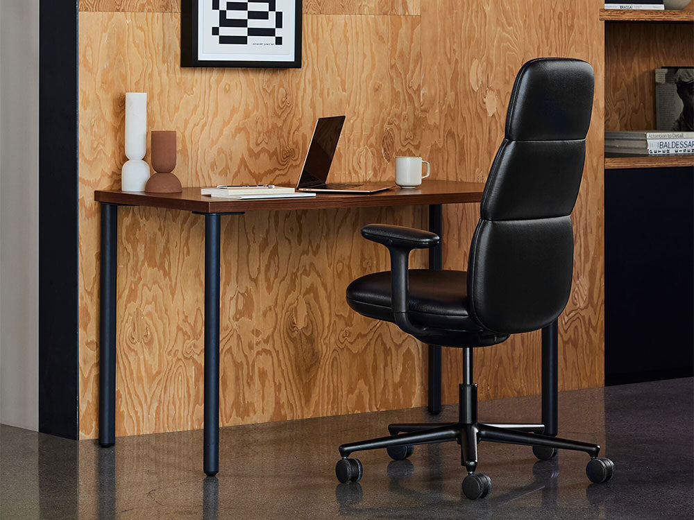 Een zwarte Asari-bureaustoel staat voor een zwart en walnootkleurig OE1-bureau in een interieur met een mid-century moderne inrichting.
