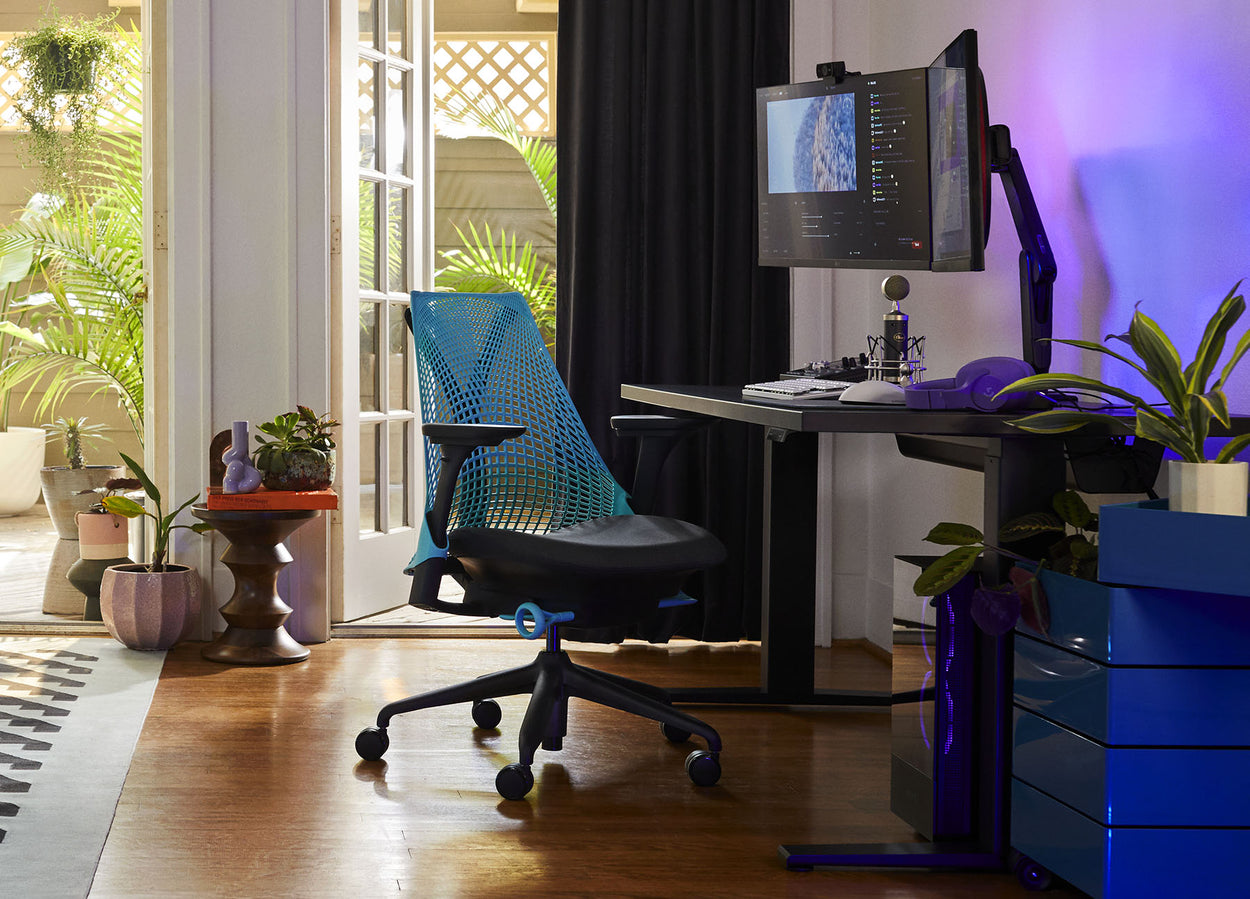 Foto van Friskk's gamingopstelling thuis, bestaande uit een Sayl-gamingstoel in zwart en oceaanblauw met een Nevi-gamingtafel in zwart
