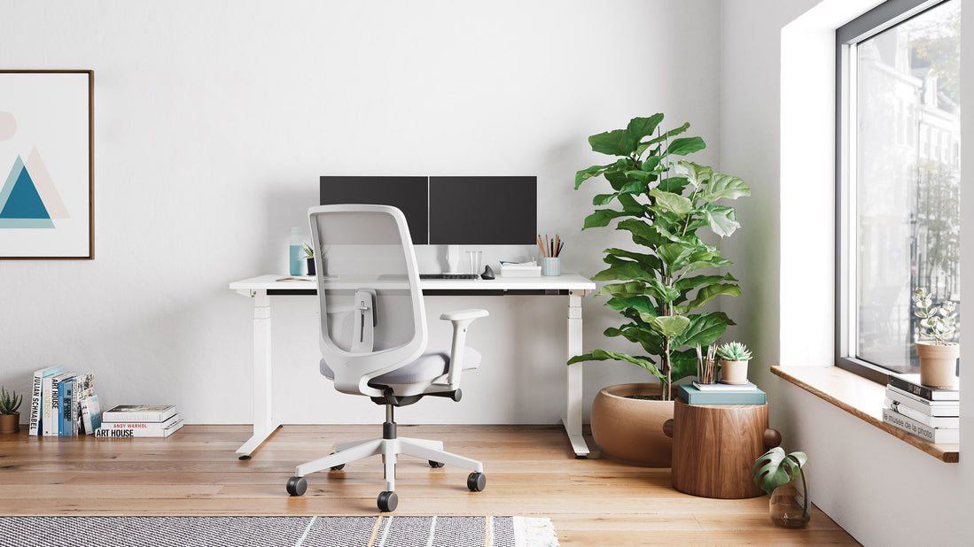 Een wit Nevi zit-sta-bureau van Herman Miller als onderdeel van een licht thuiskantoor.