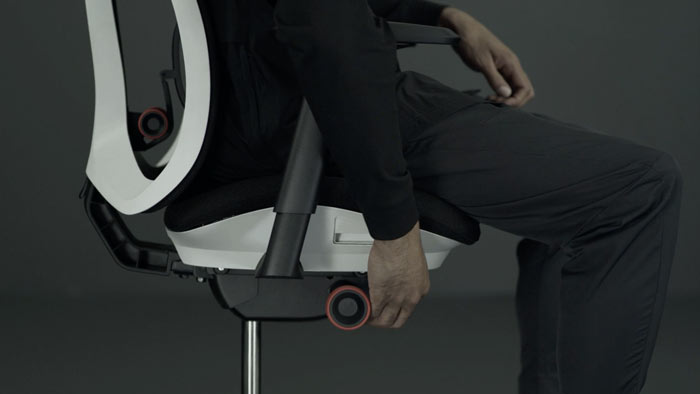 Een video van een persoon die in een wit-zwarte Vantum-gamingstoel van Herman Miller zit en naast de stoel reikt om de zithoogte aan te passen.
