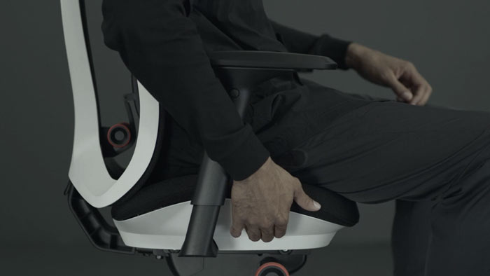 Een video van een persoon die in een wit-zwarte Vantum-gamingstoel van Herman Miller zit en naast de stoel reikt om de zitdiepte aan te passen.