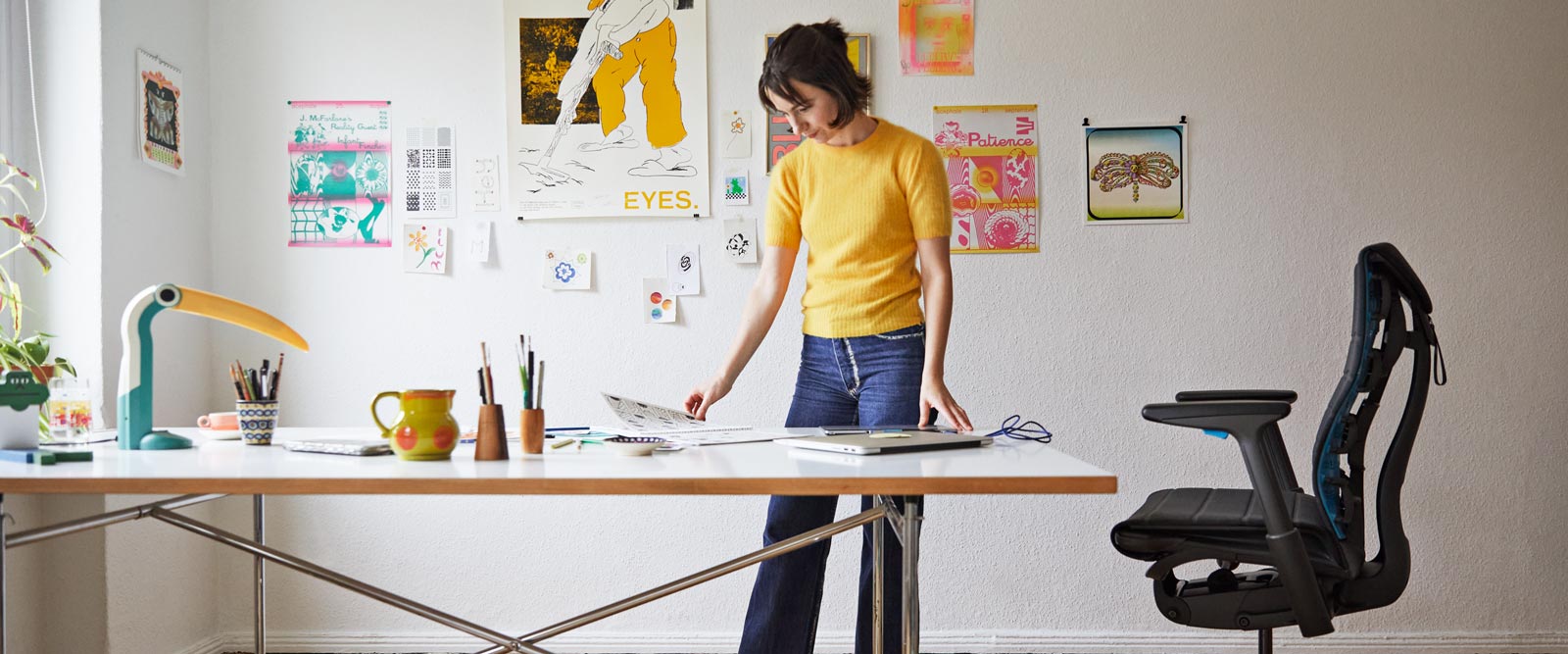 Illustrator, schilder en auteur Molly Rose Dyson stond in haar studio met een Embody-gamingstoel in zwart en cyaanblauw