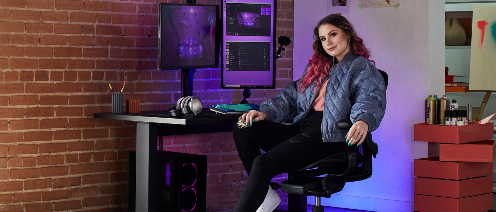 Foto van gamer Electra voor de camera, zittend op Aeron gaming onyx black  voor Nevi gaming desk in zwart met Ollin-monitor