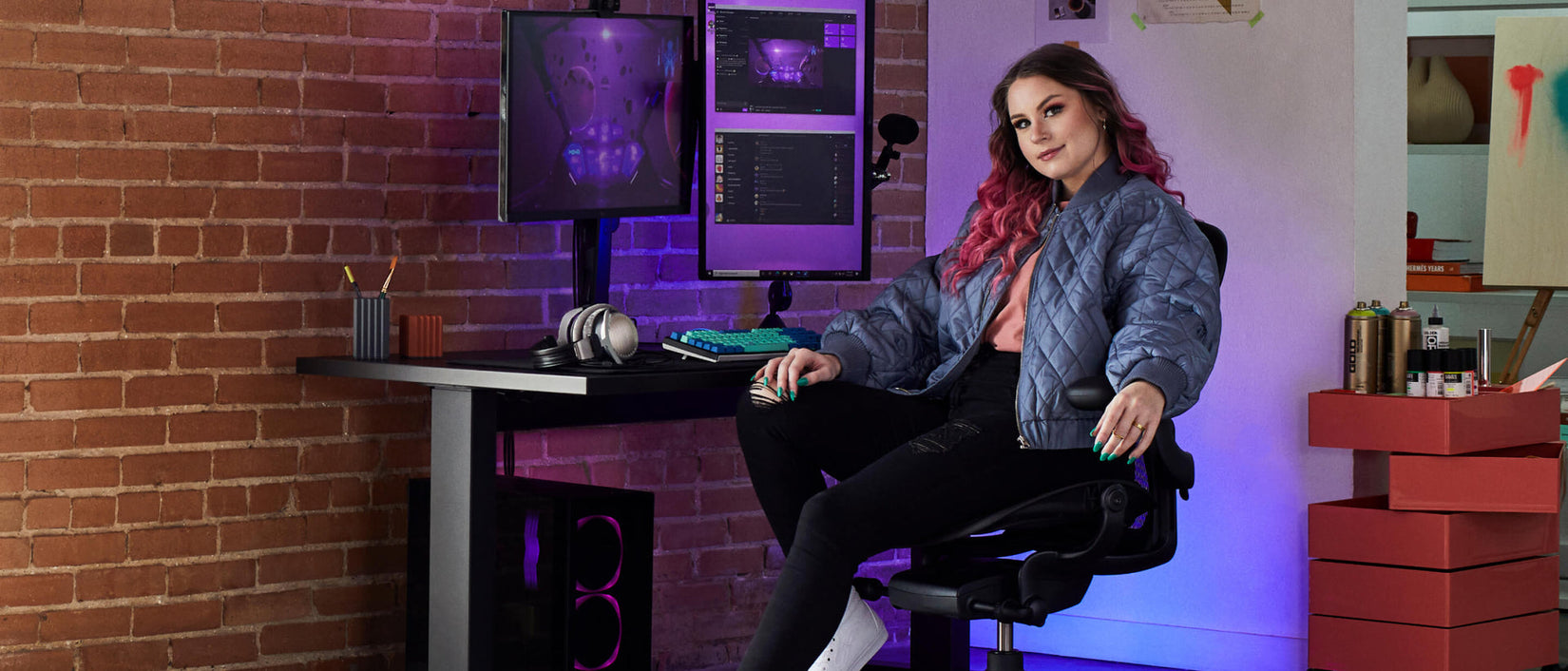 Foto van gamer Electra voor de camera, zittend op Aeron gaming onyx black  voor Nevi gaming desk in zwart met Ollin-monitor