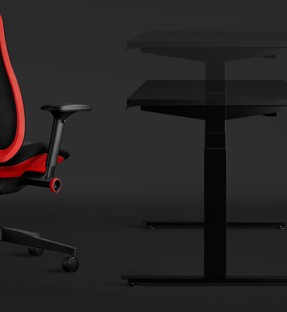 Zijaanzicht van een zwart Nevi-gamingbureau en een rode Vantum-gamingstoel van Herman Miller, waarbij het zit-sta-element van het bureau wordt benadrukt.