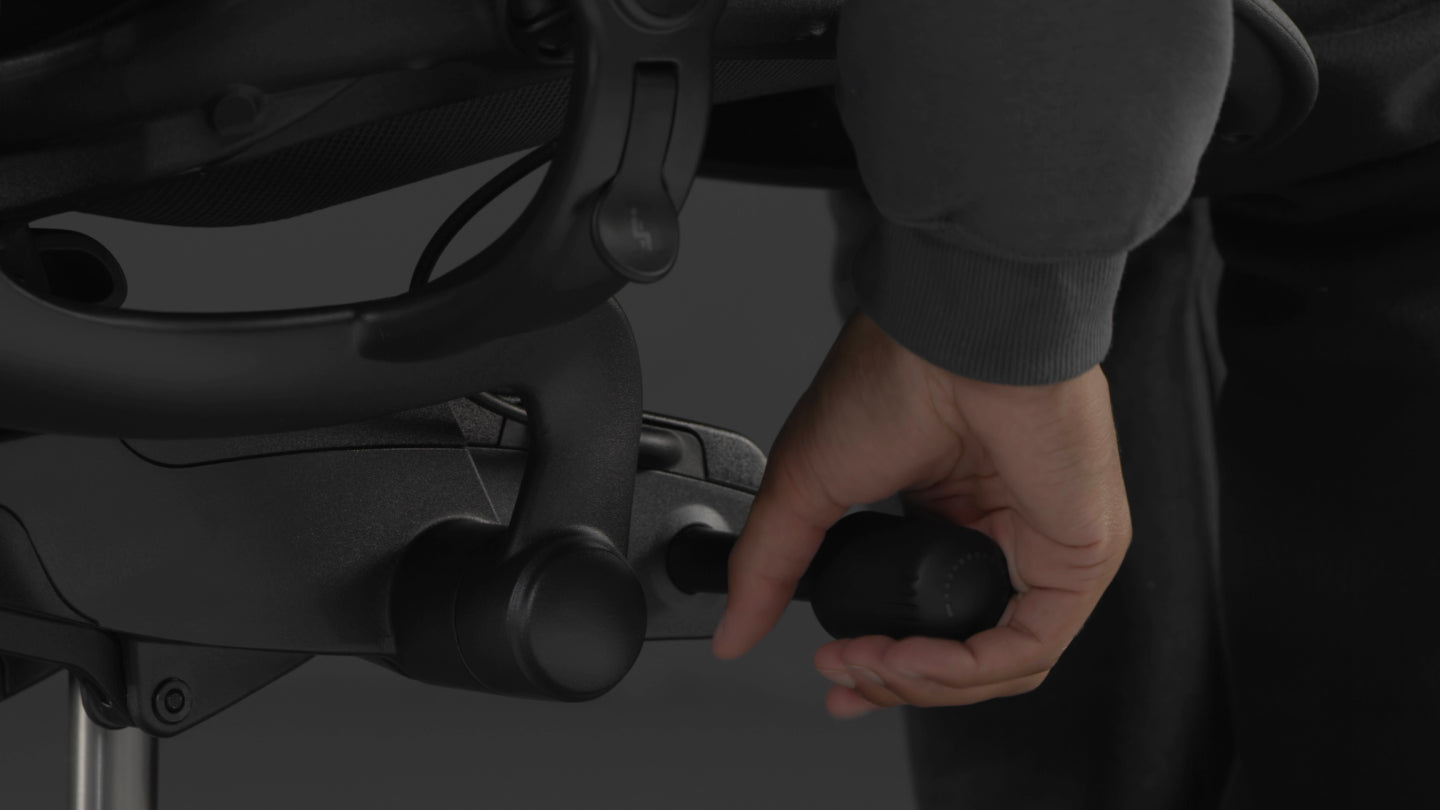 Een video van een persoon die in een zwarte Aeron-gamingstoel van Herman Miller zit en naast de stoel reikt om de kantelspanning aan te passen.
