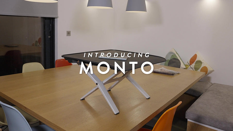 Monto Sit Stand Riser van CBS op een bureau in een vergaderruimte.
