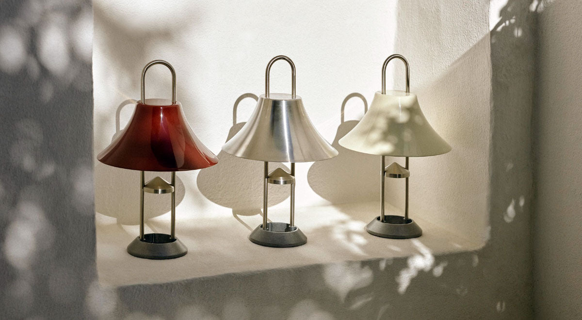 Drie HAY Mousqueton draagbare lampen in rood, zilver en wit, geplaatst in een witte nis in de muur.