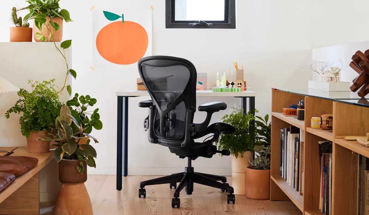 Een zwarte Aeron-bureaustoel van Herman Miller, in een thuiskantoor met een wit en blauw OE1-bureau.