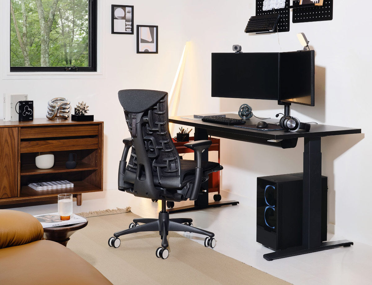 Zwarte Herman Miller Embody-gamingstoel met zwart Nevi-gamingbureau met zit-sta-functie en gamingopstelling met twee monitoren