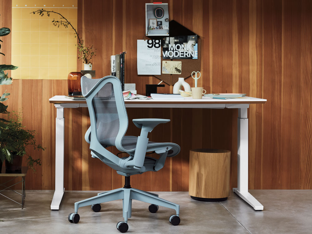 Thuiskantoorscène met Cosm-bureaustoel met lage rugleuning in gletsjergrijs en Nevi zit-sta-bureau in wit.
