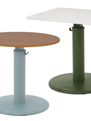 Twee OE1-sta-bureaus van Herman Miller, één met een rond walnoothouten blad en blauwe onderstel, en één met een rechthoekig wit blad en groen onderstel.