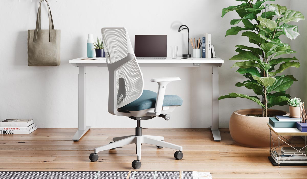 Een witte en blauwe Verus-bureaustoel van Herman Miller, geplaatst voor een wit Nevi-sta-bureau.