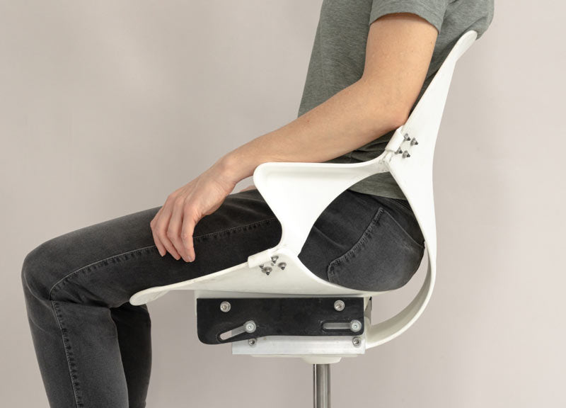 Zijaanzicht van een persoon die in een nog onafgewerkte Zeph-bureaustoel zit, waarmee de flexibiliteit van de rugleuning van de stoel wordt getoond