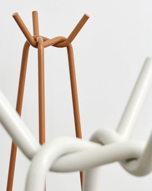 Close-up van een gebreide kapstok van HAY, waarop de metalen buizen te zien zijn die aan de bovenkant met elkaar zijn verbonden.