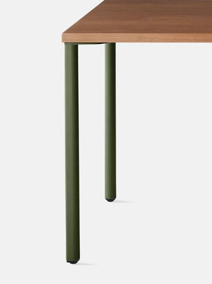 Close-up vooraanzicht van een groen en walnootkleurig OE1-bureau van Herman Miller, met het druppelvormige ontwerp van de poten.