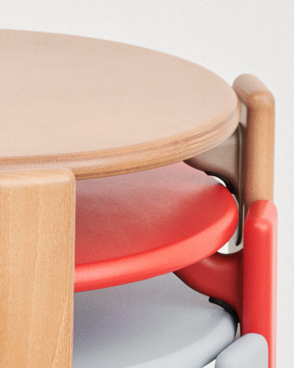 Close-up van drie Rey-stoelen van HAY, in beuken, rood en blauw, op elkaar gestapeld.