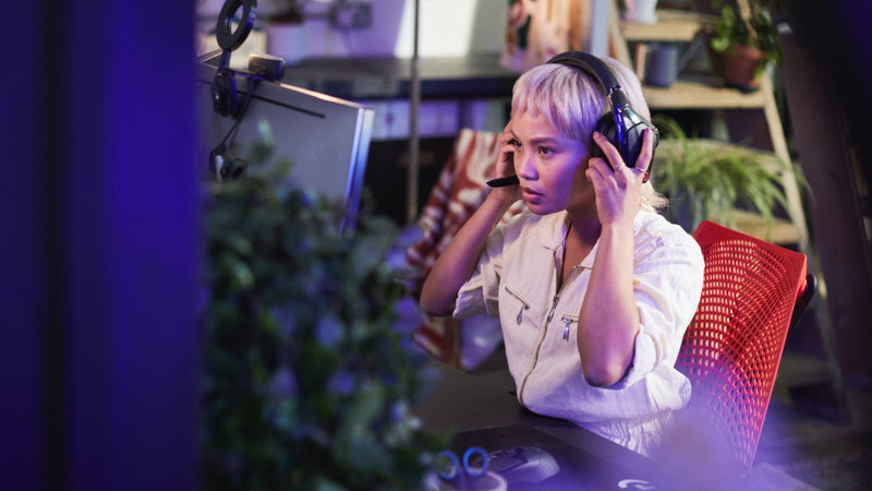 Een video van een vrouw die in een rood-zwarte Sayl-gamingstoel van Herman Miller zit, een koptelefoon opzet en een computerspel speelt.