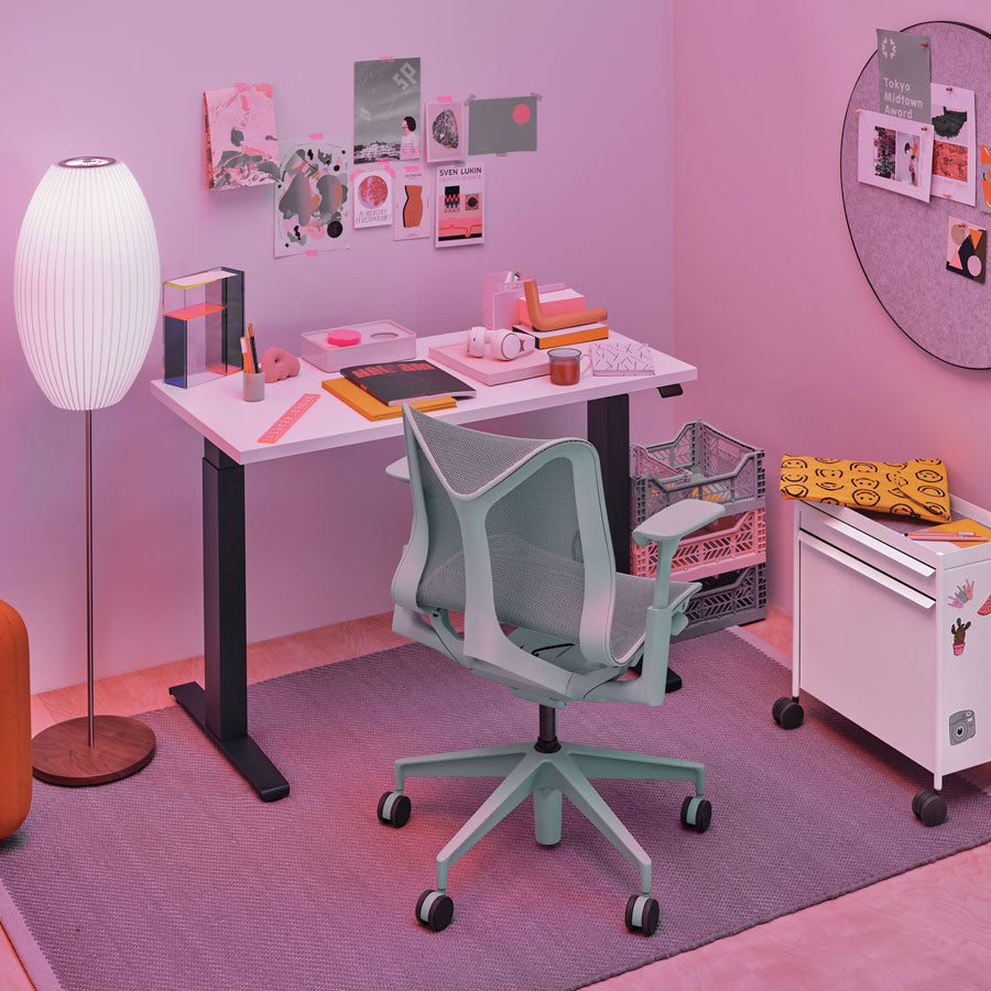 Thuiskantoor met Cosm-bureaustoel met lage rugleuning in gletsjergrijs voor een Nevi zit-sta-bureau met zwarte poten en wit blad