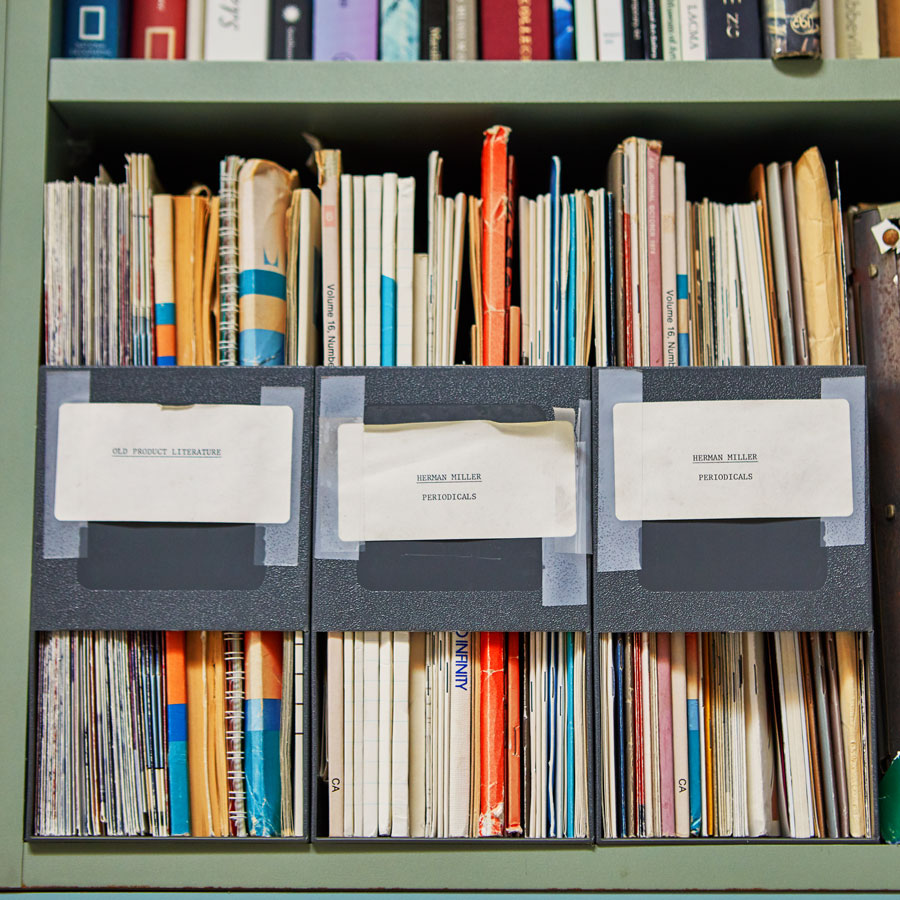 Afbeelding van een plank met ontwerp- en onderzoeksdossiers die allemaal betrekking hebben op het productontwerp en de productontwikkeling van Herman Miller